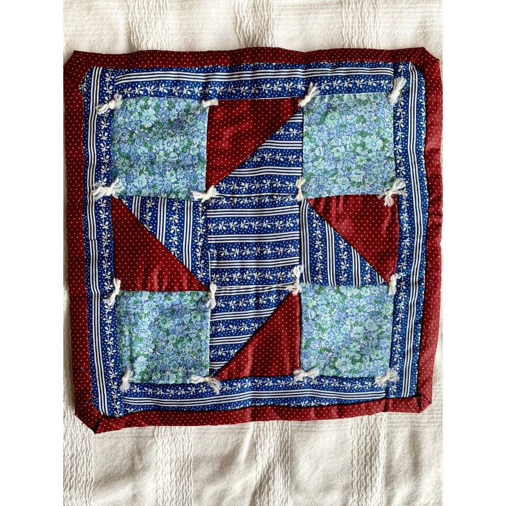 Handmade quilted mat 11 X 11. Multicolor front. Red back.